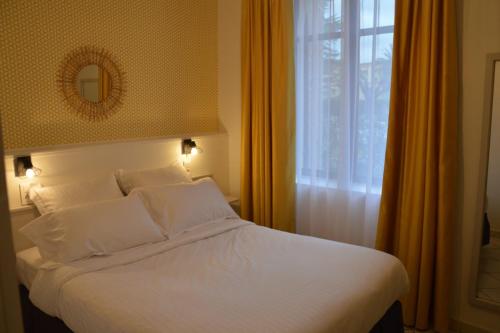a bedroom with a bed with white sheets and a window at Hotel Castellamar in Sainte-Maxime
