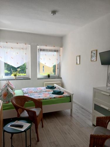 a bedroom with a bed and a table and two windows at Pension Küfner in Markkleeberg