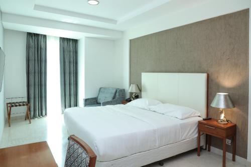a bedroom with a large white bed and a chair at MGM Service Apartment by Savills Oman in Muscat