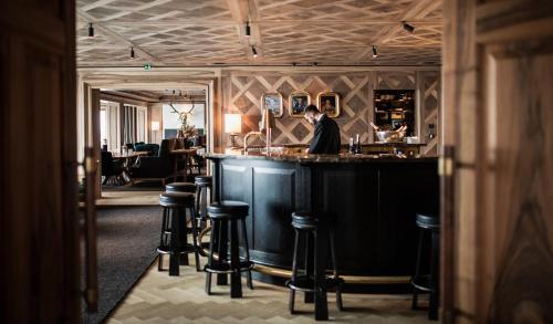a man standing at a bar in a restaurant at Hotel Almhof Schneider in Lech am Arlberg