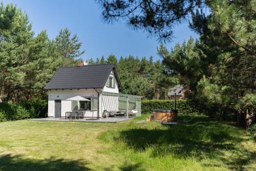 a white cottage with a black roof in a yard at LAS i MORZE in Czarny Młyn
