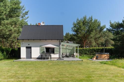 a small white building with a deck in a yard at LAS i MORZE in Czarny Młyn