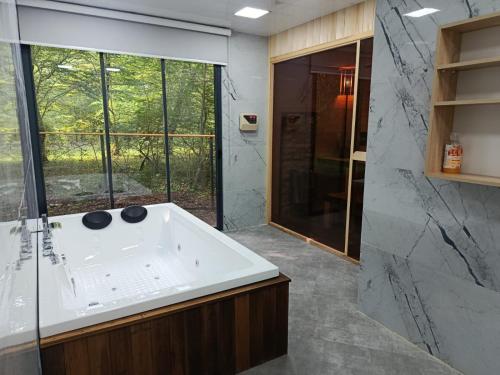 ein Badezimmer mit weißer Badewanne und Dusche in der Unterkunft Rıver Forest Hotel in İsmayıllı