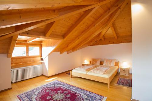 a bedroom with a bed and a window and wooden ceilings at Tinnerhof in Appiano sulla Strada del Vino