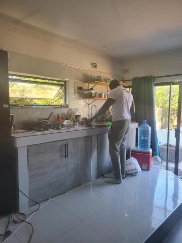 a man standing in a kitchen preparing food at Whispering Woods in Kafue