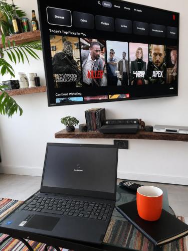 a laptop computer sitting on a desk with a tv at Whispering Woods in Kafue