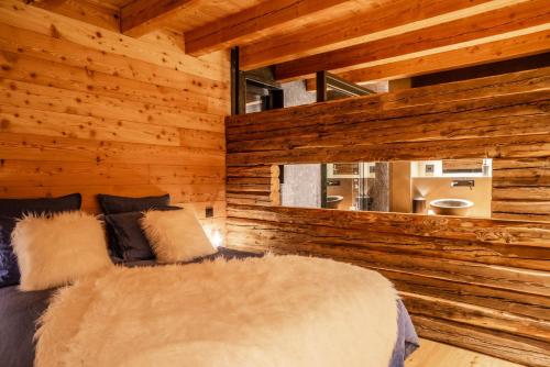 a bedroom with wooden walls with a bed and a window at Beleza in La Salle-les-Alpes