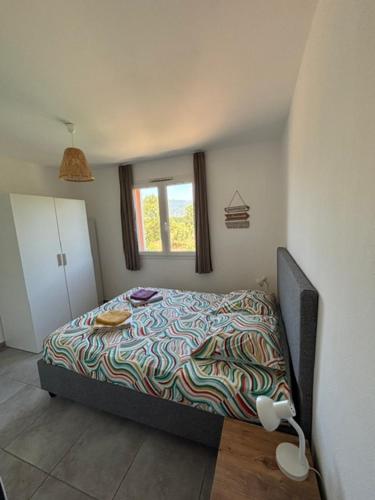 a bedroom with a bed with a colorful blanket at Appartement T2 moderne - Résidence Lecci - Piscines & proche Mer in Lecci