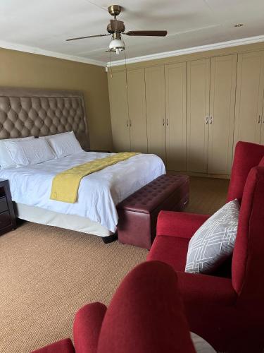 a bedroom with a large bed and two red chairs at Diamo Guest House in Roodeplaat