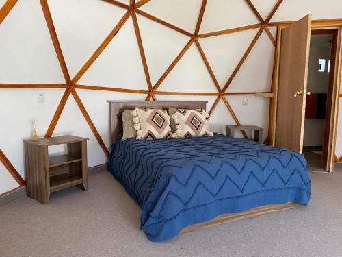 a bedroom with a blue bed in a yurt at GlampingWoodzen in Villa del Carbón