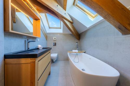 a bathroom with a tub and a sink and skylights at Le Stam in La Salle-les-Alpes
