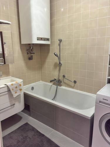 a bathroom with a tub and a sink and a washing machine at Appartement Landzeit im Waldviertel in Steinbach
