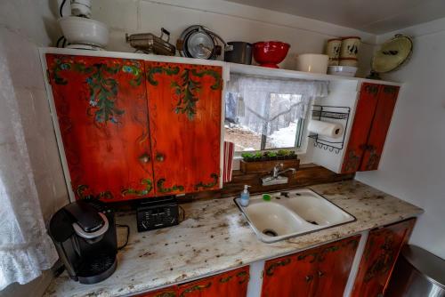 a kitchen with red cabinets and a sink at Cottage On The Stream Sundance, Utah in Sundance