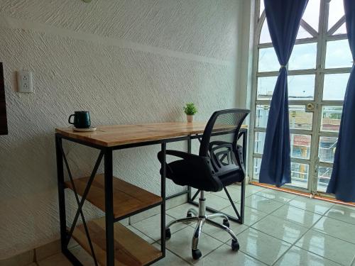 a desk with a chair in a room with a window at Amueblados Casa Conchita in León