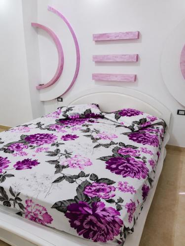 a bedroom with a bed with purple flowers on it at ben mesaaoud in Kelibia