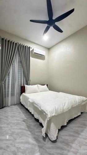 a bedroom with a bed with a ceiling fan at Baba Homestay in Macang