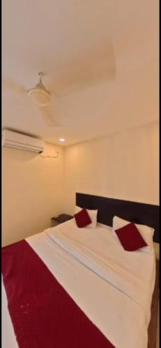 a bedroom with a white bed with red pillows at HOTEL MEREDIAN GRAND INn in Shamshabad