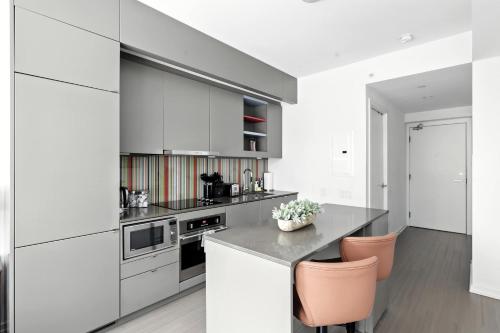 a kitchen with white cabinets and pink chairs at Entertainment District Gem Walk to CN Tower in Toronto