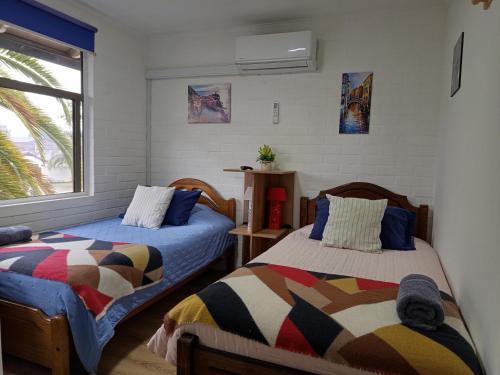 a bedroom with two beds and a window at Hostal Rucatremo in Curicó