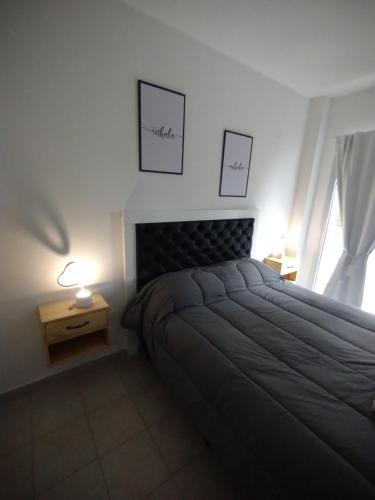 a bedroom with a bed and a window with two pictures on the wall at WB1c in Puerto Madryn