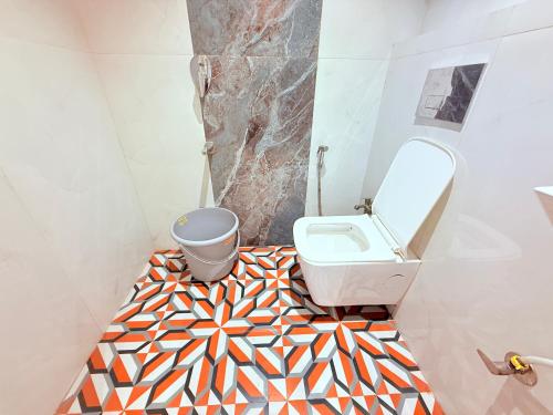 a bathroom with a toilet and a geometric floor at Hotel Iris Inn - Near Lodha Palava, Dombivali in Dombivli