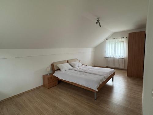 a white bedroom with a bed and a window at Kuća za odmor NIMA in Gospić