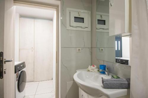 a white bathroom with a sink and a mirror at Ermira in Agios Nikolaos
