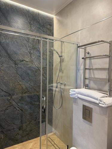 a bathroom with a glass shower stall with towels at Benefit Boutique Hotel in Odesa
