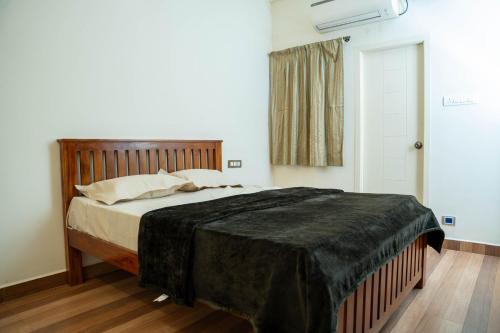 a bedroom with a bed with a black blanket on it at Sivam Villa-Kovalam in Covelong