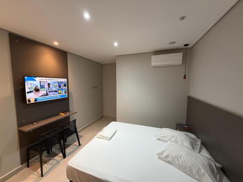 a bedroom with a bed and a tv on the wall at Wish Suítes in Campinas