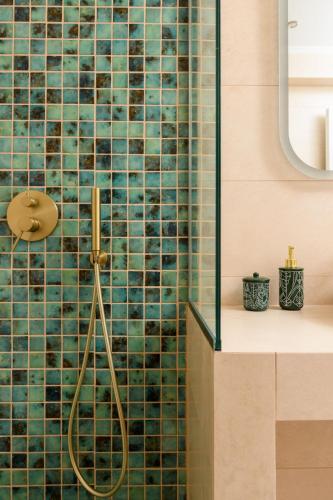 a bathroom with a shower with green tiles at Oasis deluxe apartments in Skala Rachoniou