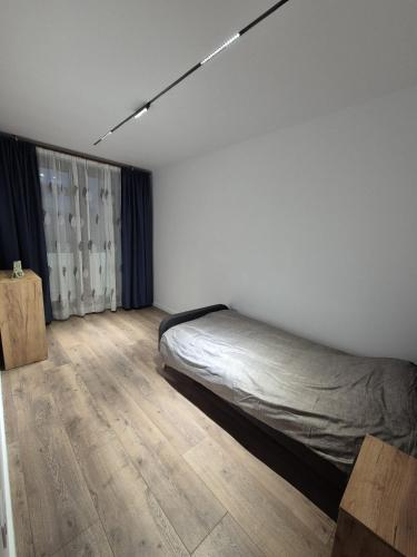a bedroom with a bed and a wooden floor at The Garden Apartment in Bîrlad