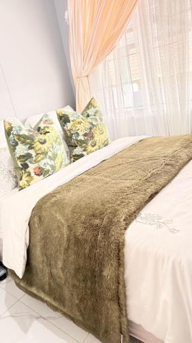 a bed with a blanket and pillows and a window at 33OnPangolin B&B in Nelspruit