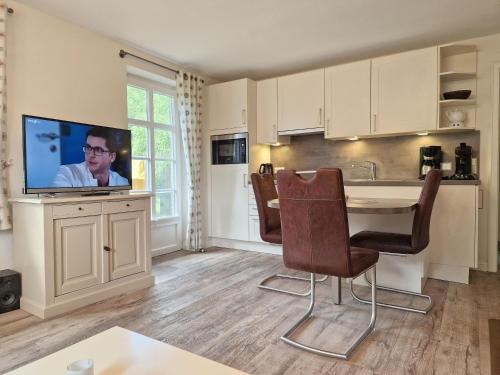 a kitchen with a table with chairs and a tv at Goting-Sonne in Borgsum