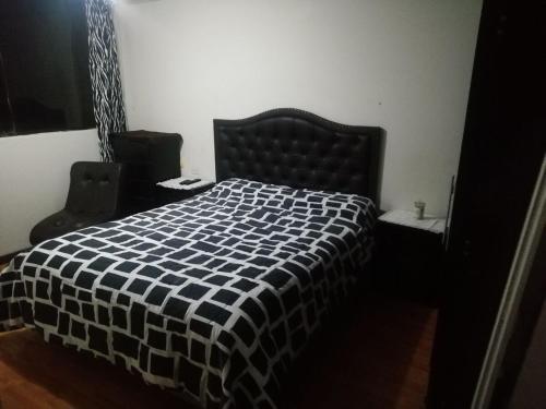 a bedroom with a bed with a black and white checkered blanket at Yanahuara Urb Ibargüen in Arequipa