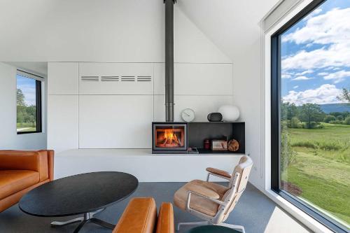 a living room with a fireplace and a table and chairs at Valley View - Renovated Cottage New Addon and Pool in Copake