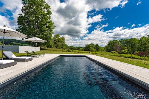 a swimming pool with two chairs and an umbrella at Valley View - Renovated Cottage New Addon and Pool in Copake