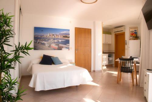a bedroom with a white bed with a painting on the wall at Apartamentos la barca in Benidorm