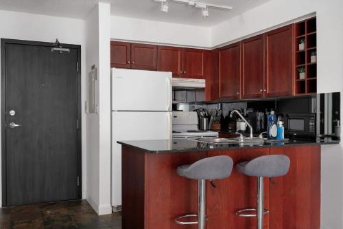 a kitchen with brown cabinets and a white refrigerator at Modern King Suite Steps to Eaton Centre in Toronto