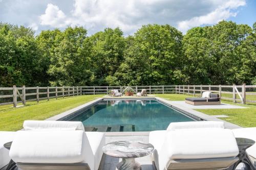 a swimming pool with white chairs and a fence at Whimsy Woods - 14 Acre Millbrook Estate with Pool in Millbrook