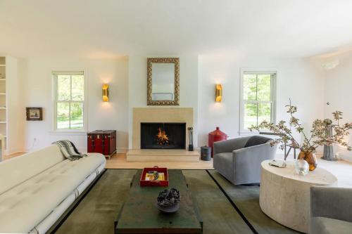 a living room with a couch and a fireplace at Whimsy Woods - 14 Acre Millbrook Estate with Pool in Millbrook