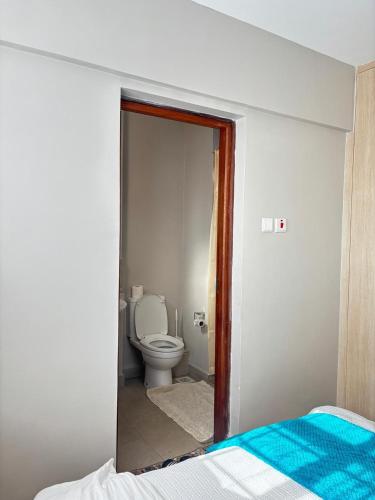 a bathroom with a toilet and a bed in a room at Kasarani trm in Nairobi