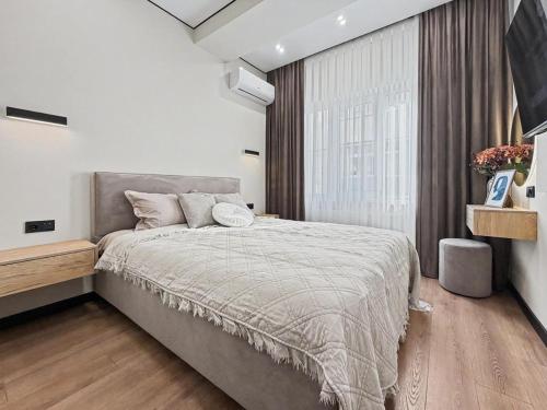 a bedroom with a bed and a large window at Rent&live beautiful apartment in Chişinău
