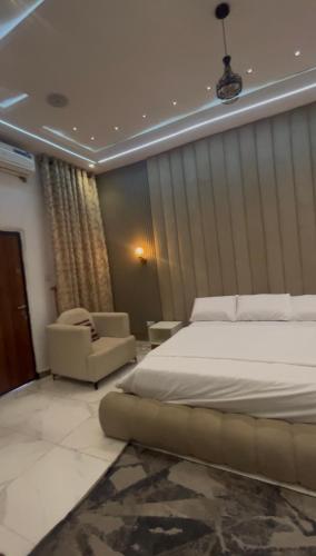 a bedroom with a bed and two chairs in it at Emilomo Luxury Apartment in Idowu