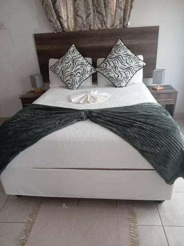 a bed with a black and white blanket and pillows at Kgajane Guest House in Molepolole