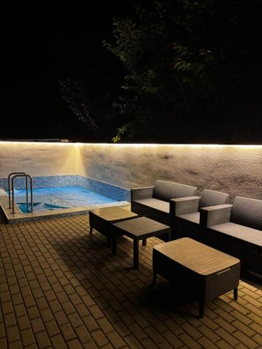 a swimming pool with a table and benches next to a patio at Apartmány U Kempu in Dolní Lomná