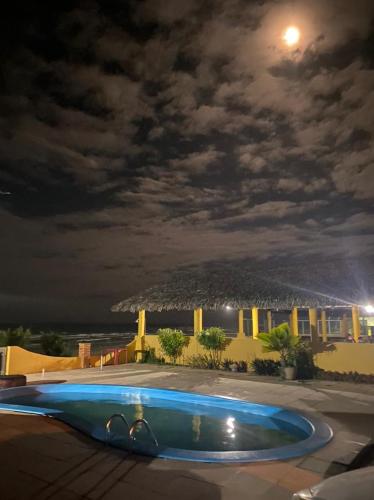 a swimming pool in front of a house at night at Pousada o Èdio in Beberibe
