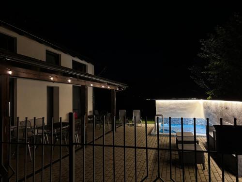 a fence with chairs and a swimming pool at night at Apartmány U Kempu in Dolní Lomná