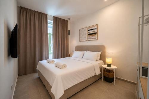 a bedroom with a white bed and a television at The Simon Residences - Marina Escape in Olhão