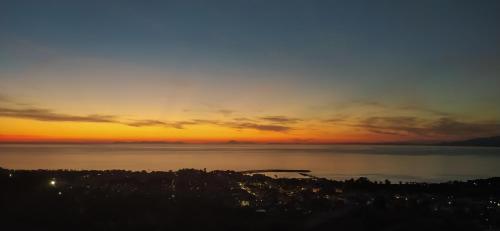 a sunset over the water with a city in the distance at TheA Upper Blue in Kyparissia